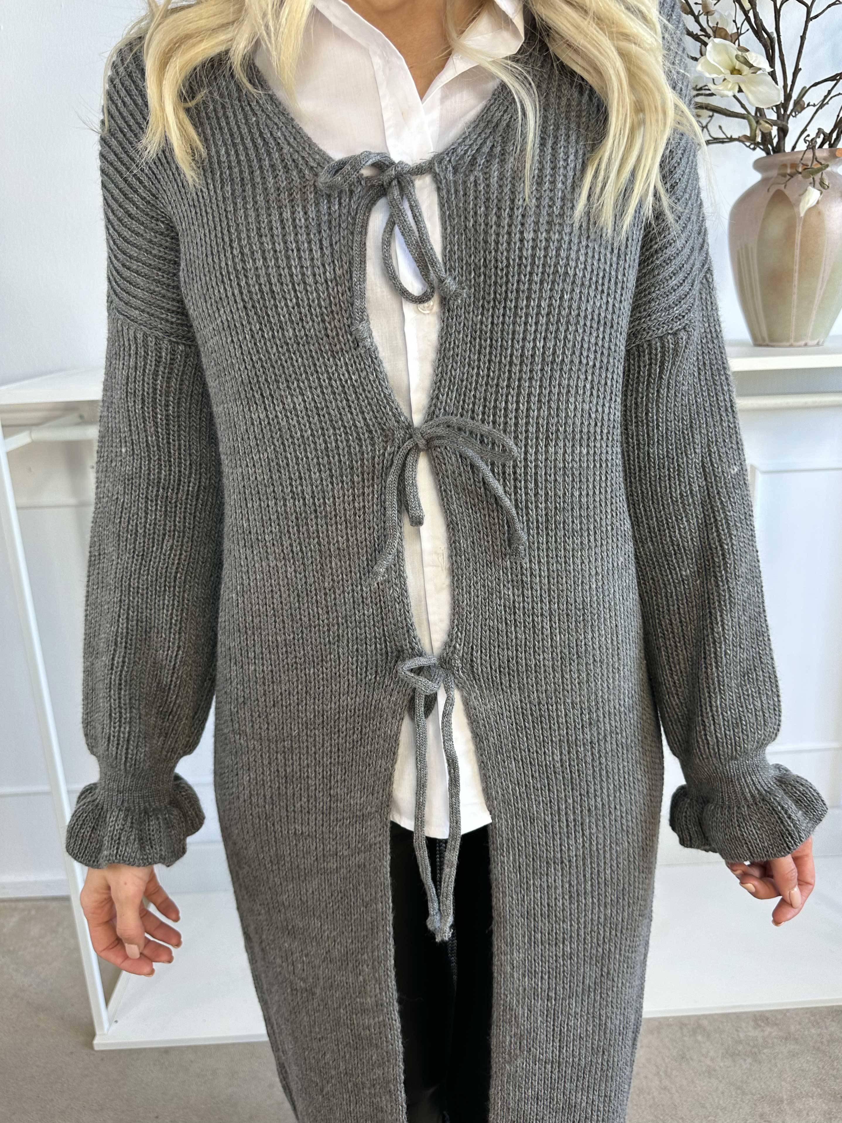 Catalina - Lång stickad kofta med rosetter och volangkant