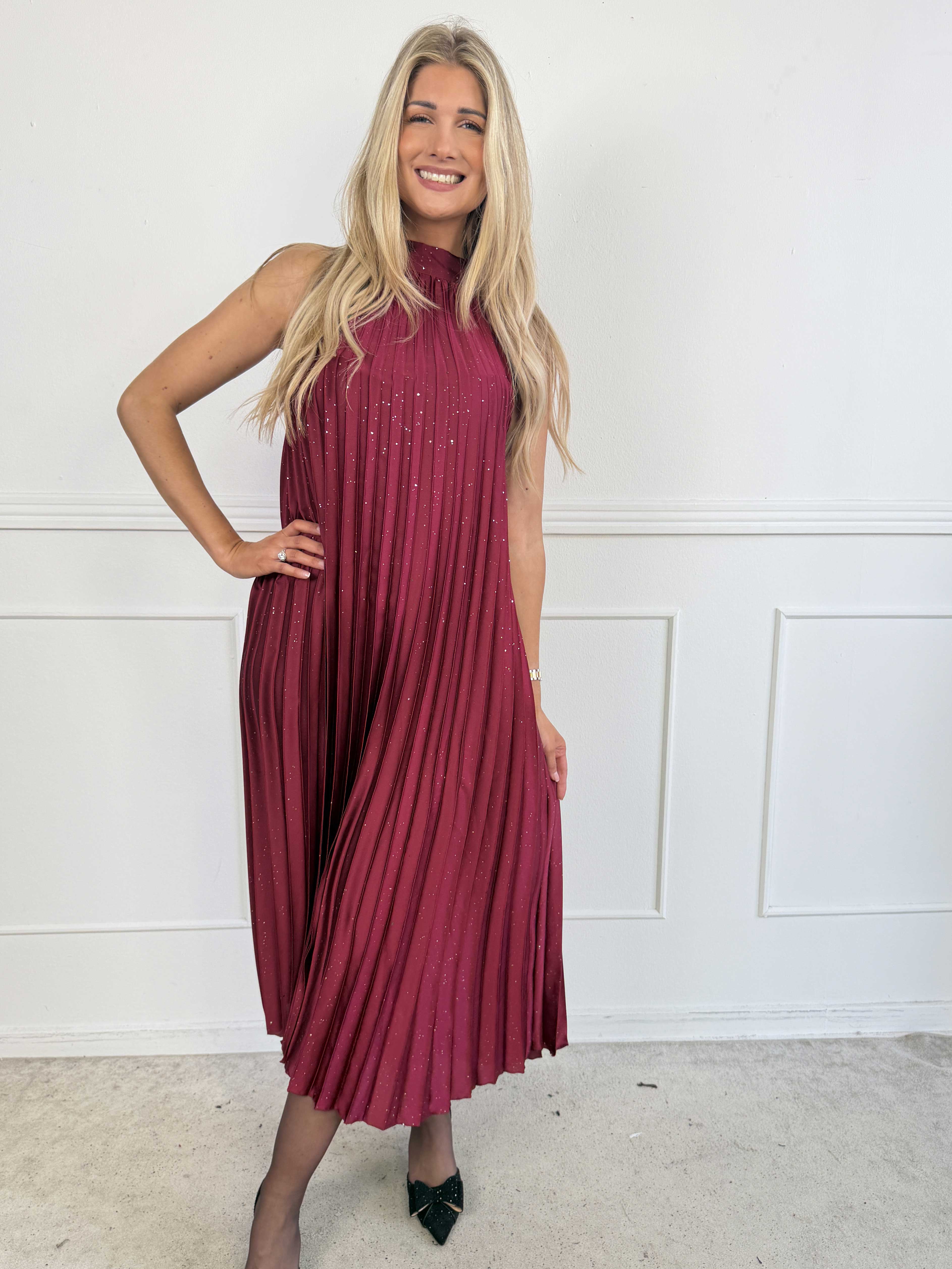 Madison Glitter - Lång plisserad klänning med fina glitterdetaljer, volangkant och en elegant rosett i nacken