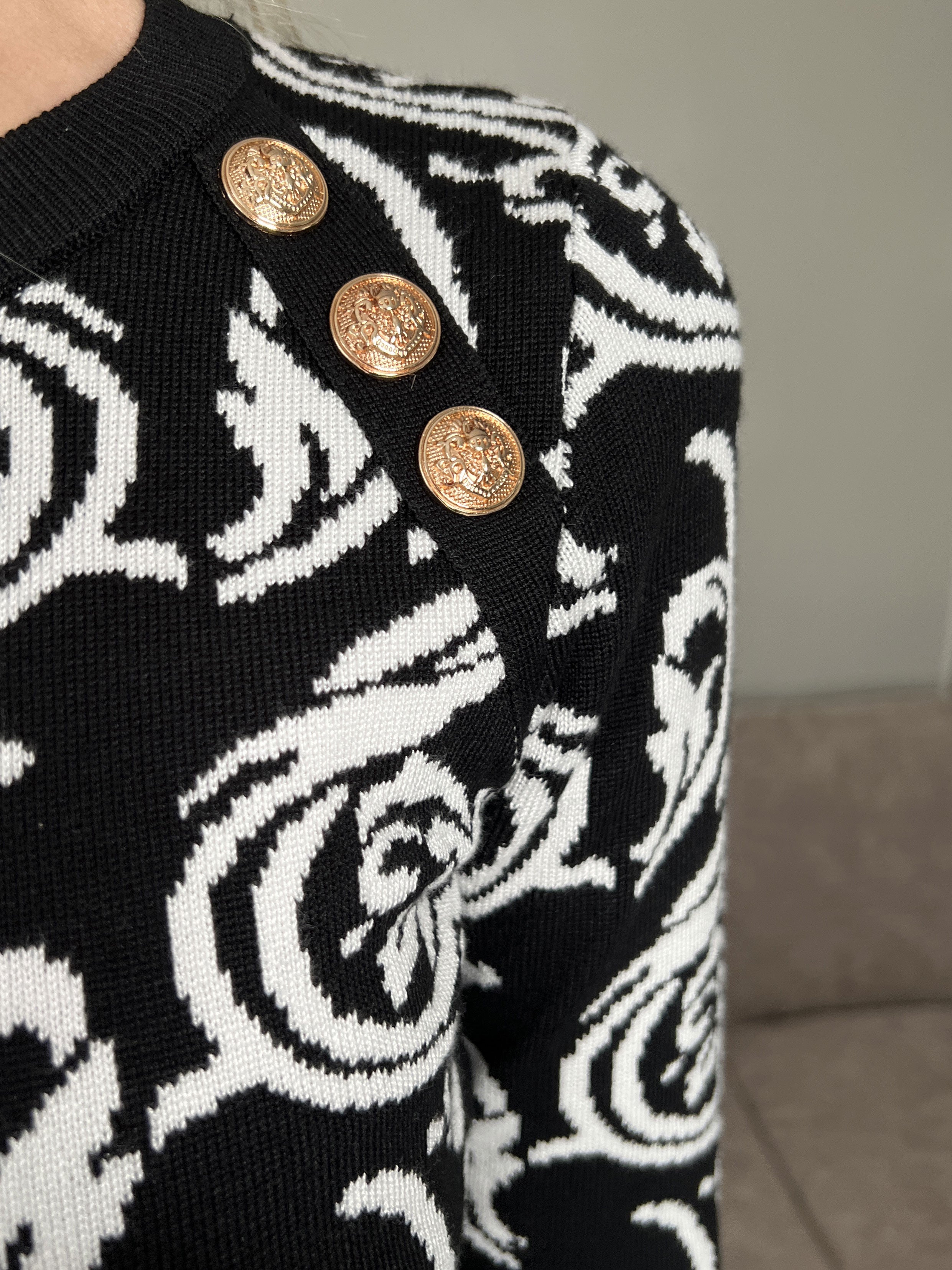 Lidia - Svart stickad klänning med vitt mönster och guldknappar