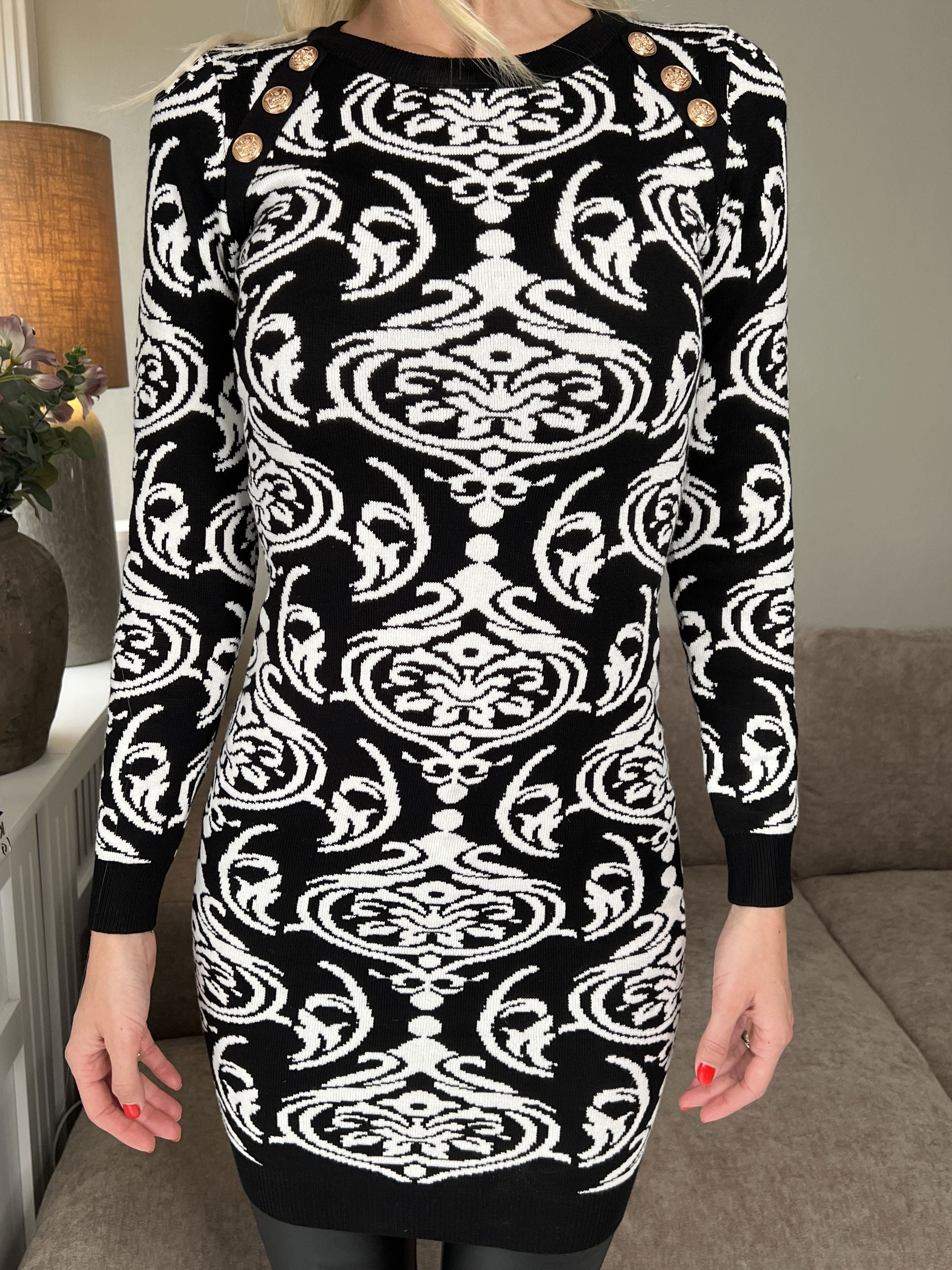 Lidia - Svart stickad klänning med vitt mönster och guldknappar